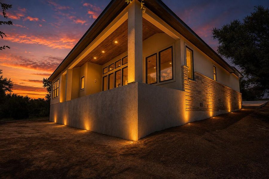 Dramatic up-lighting illuminates this elegant residence against a vibrant sunset.