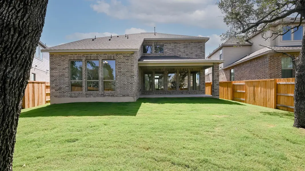 Back of property featuring brick siding, a fenced backyard, and roof with shingles
