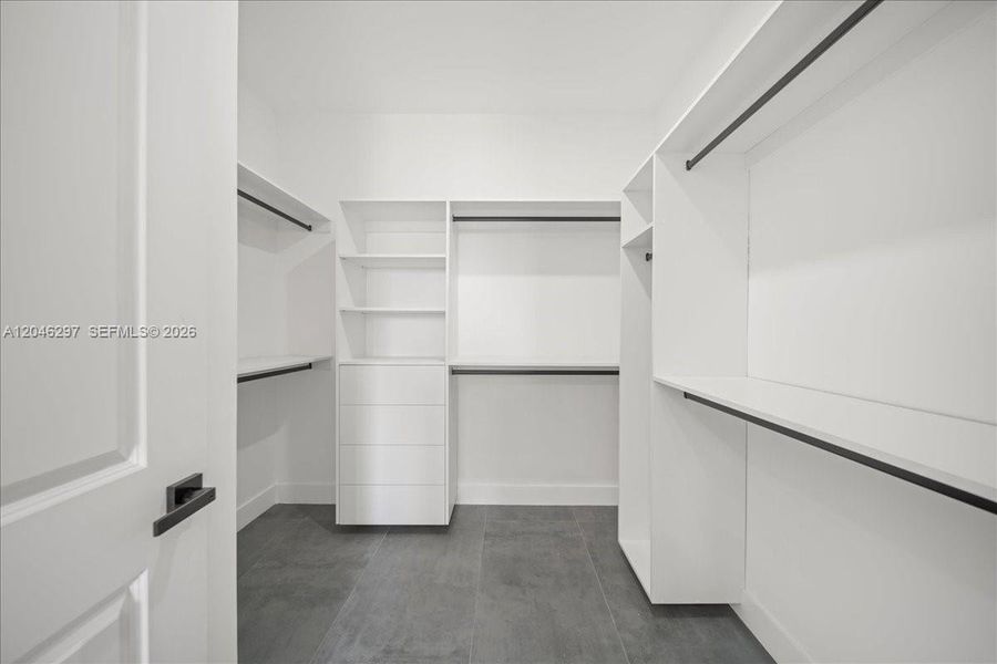 The expansive closet offers built-in shelving, drawer storage, and abundant hanging space, creating a clean and functional luxury wardrobe experience. The expansive closet offers built-in shelving, drawer storage, and abundant hanging space, creating a clean and functional luxury wardrobe experience.