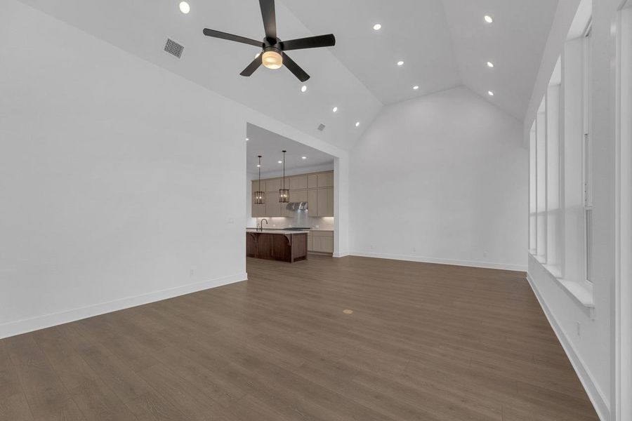Unfurnished living room featuring high vaulted ceiling, dark wood-type flooring, recessed lighting, and a ceiling fan Unfurnished living room featuring high vaulted ceiling, dark wood-type flooring, recessed lighting, and a ceiling fan