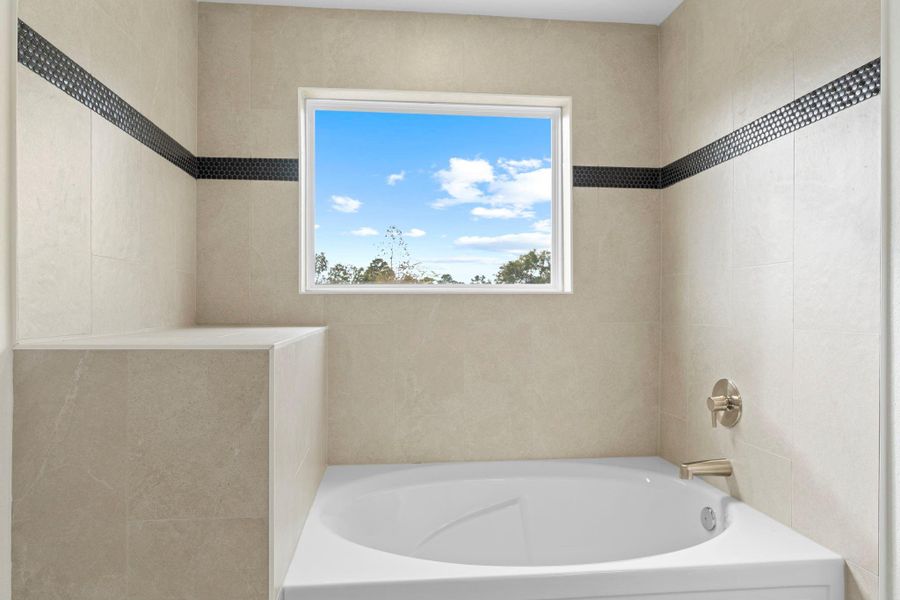 Look at the custom detail that this spa primary bathroom has!  Deep soaker tub to bubble you stress away to the stunning shelf for towels and decoration for your custom bath time!  Even down to the chic bathroom faucet.