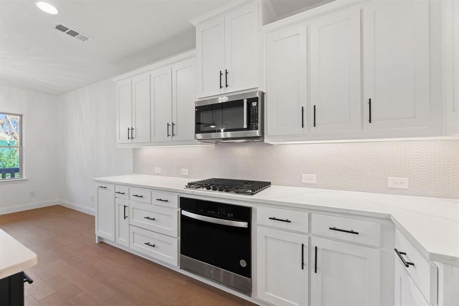 Kitchen featuring tasteful backsplash, white cabinets, stainless steel appliances, light wood-style floors, and recessed lighting Kitchen featuring tasteful backsplash, white cabinets, stainless steel appliances, light wood-style floors, and recessed lighting