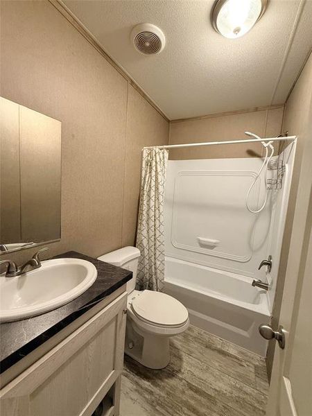 Bathroom featuring shower / bath combo, vanity, a textured ceiling, and light wood finished floors