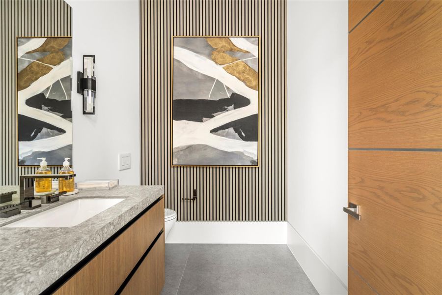 Sculptural powder bath with slatted wood accent wall and Milan stone counter. In addition to this powder bath, there is another powder room and full bath on the first floor. Sculptural powder bath with slatted wood accent wall and Milan stone counter. In addition to this powder bath, there is another powder room and full bath on the first floor.