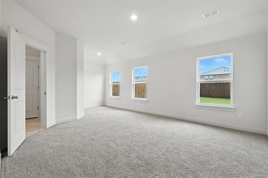 Empty room featuring light colored carpet, healthy amount of natural light, and recessed lighting