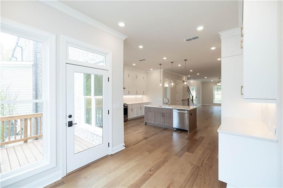 Kitchen featuring sink, decorative light fixtures, a center island with sink, stainless steel appliances, and white cabinets