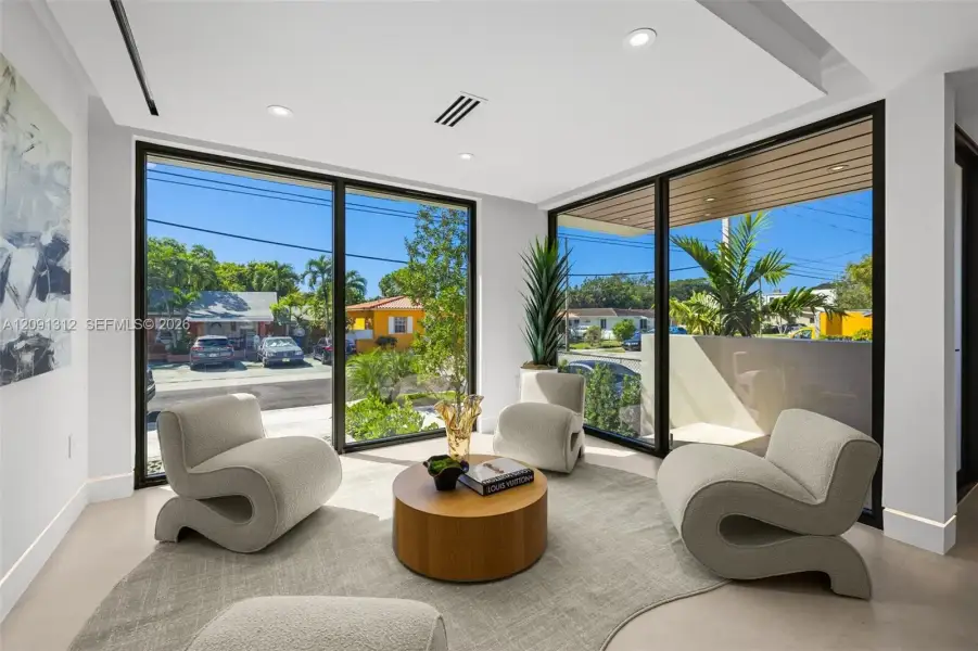 Floor-to-ceiling windows with black frames, recessed ceiling lighting, smooth finish flooring, and a tray ceiling detail Floor-to-ceiling windows with black frames, recessed ceiling lighting, smooth finish flooring, and a tray ceiling detail