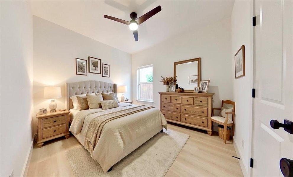 Spacious room featuring vaulted ceilings, light wood-finish flooring, and a modern ceiling fan