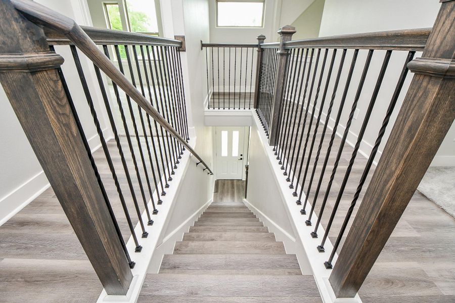 The photo showcases an elegant staircase with dark wood banisters and modern, black metal spindles, complemented by light gray wood flooring and crisp white walls. The photo showcases an elegant staircase with dark wood banisters and modern, black metal spindles, complemented by light gray wood flooring and crisp white walls.