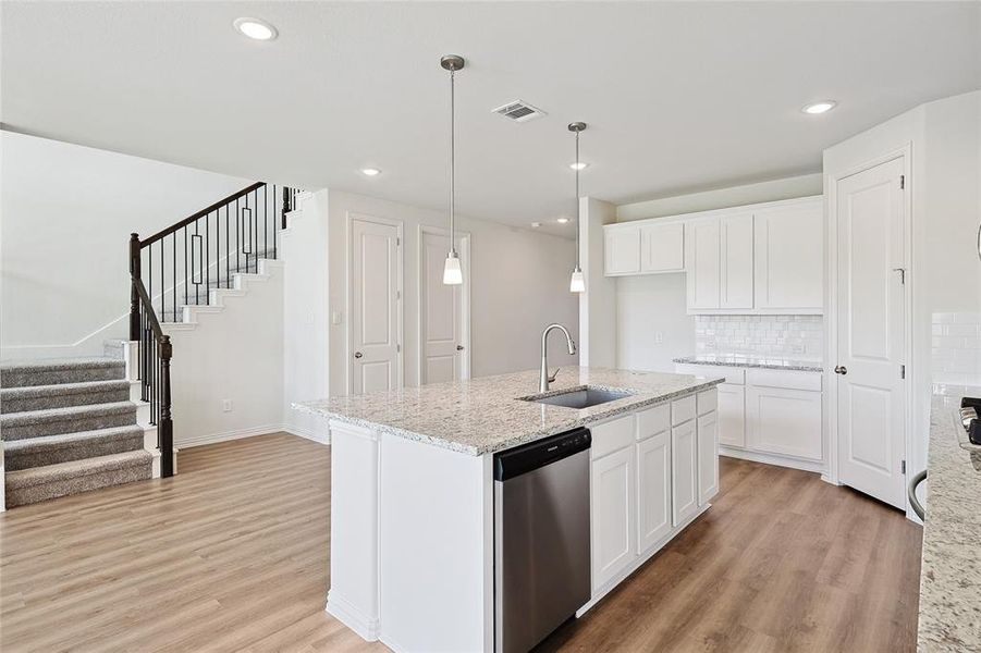 Kitchen featuring white cabinetry, dishwasher, sink, and light hardwood / wood-style floors