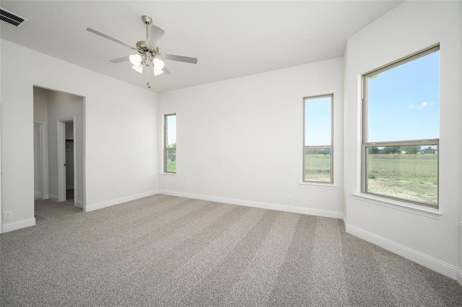 Carpeted spare room featuring ceiling fan and a healthy amount of sunlight