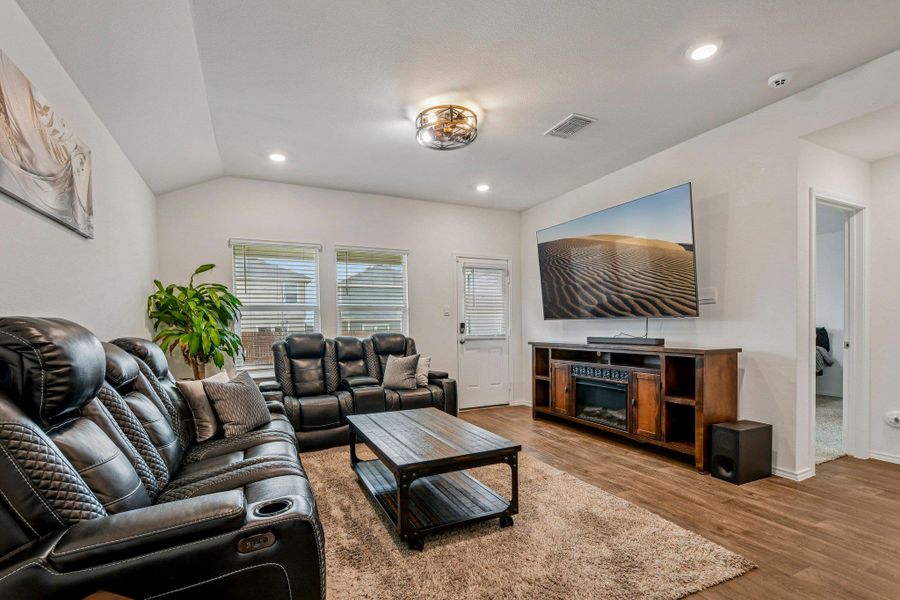 Living room with wood finished floors, recessed lighting, and vaulted ceiling