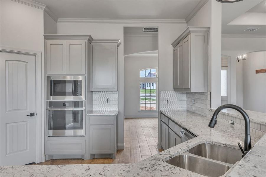 Kitchen with light hardwood / wood-style flooring, light stone counters, tasteful backsplash, and sink