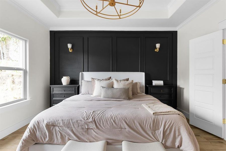 Bedroom featuring multiple windows, a raised ceiling, and ornamental molding