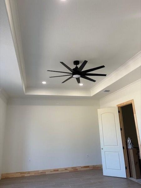 Unfurnished room with a tray ceiling, ceiling fan, wood tiled floors, recessed lighting, and crown molding