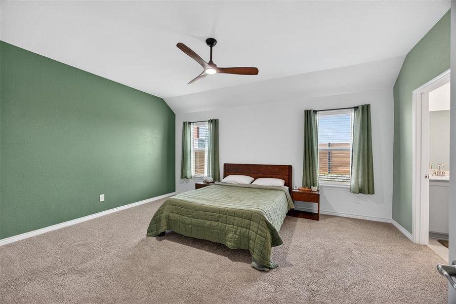 Bedroom with vaulted ceiling, carpet floors, and ceiling fan