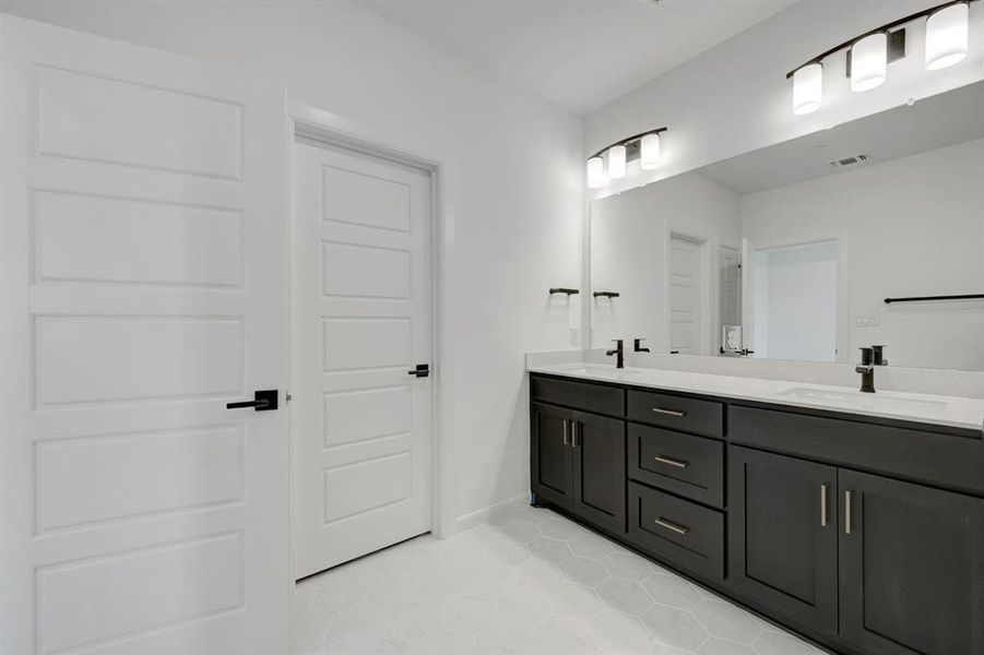 Dual vanity with dark wood cabinetry, white countertops, and matte black fixtures Dual vanity with dark wood cabinetry, white countertops, and matte black fixtures
