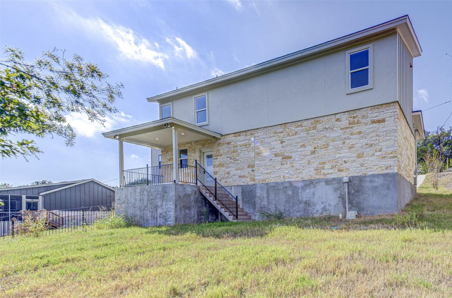Rear view of property featuring stone siding and stairs