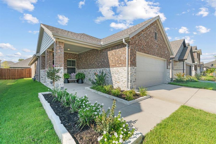 View of side of home featuring an attached garage, brick siding, stone siding, concrete driveway, and roof with shingles View of side of home featuring an attached garage, brick siding, stone siding, concrete driveway, and roof with shingles