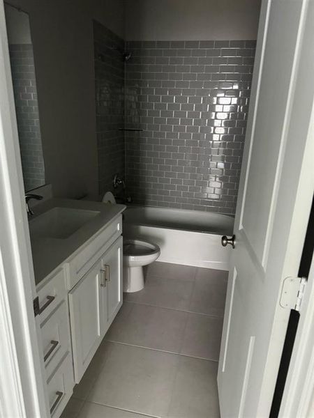 Full bathroom featuring tile patterned flooring, vanity, toilet, and tiled shower / bath