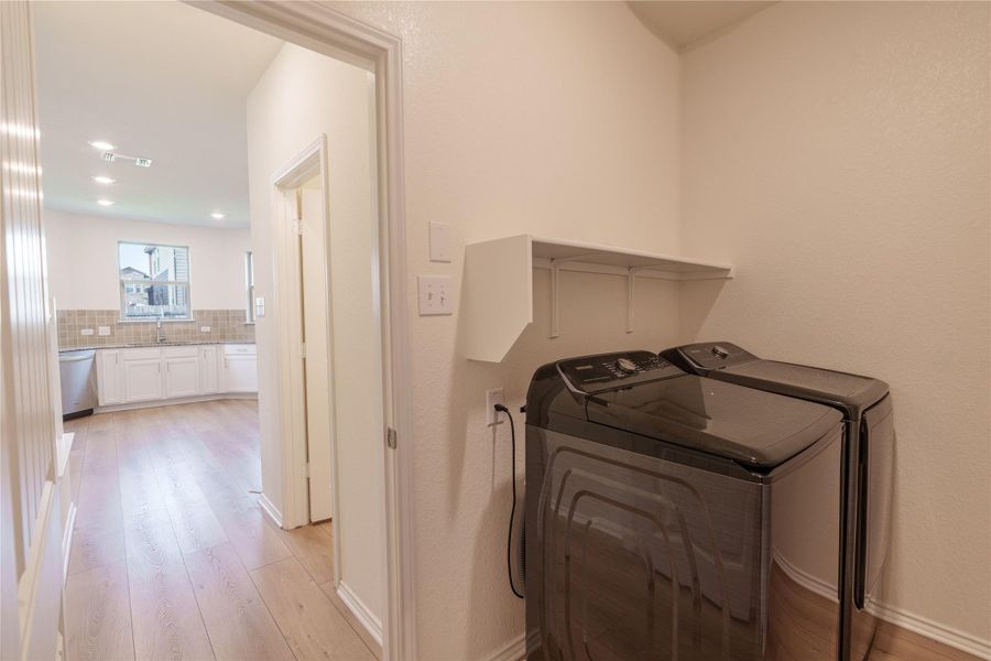 Functional laundry space featuring modern appliances and convenient overhead shelving. Functional laundry space featuring modern appliances and convenient overhead shelving.