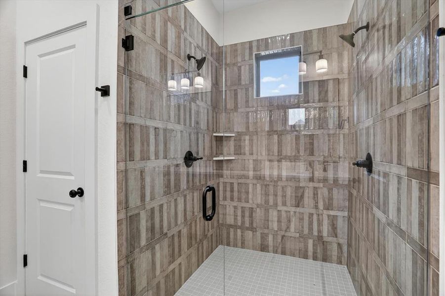 Spacious walk-in shower featuring glass enclosure, patterned tile walls, and a square window
