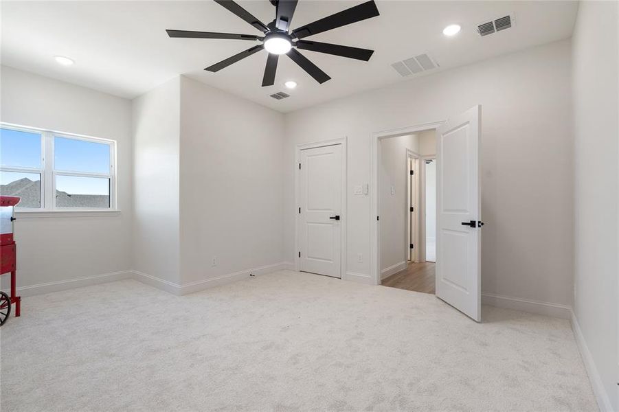 Unfurnished bedroom featuring ceiling fan and light colored carpet