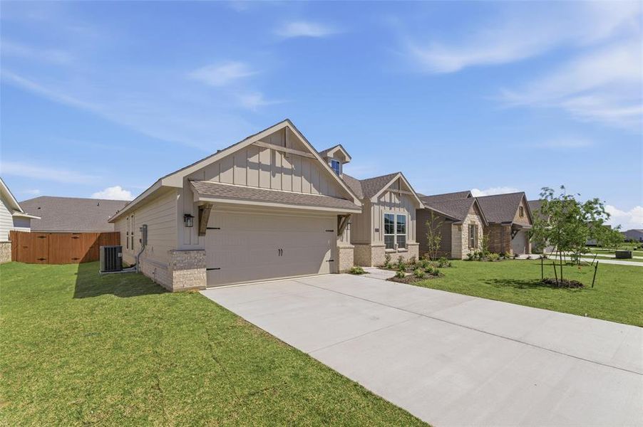 Craftsman house with board and batten siding, brick siding, a garage, driveway, and a front lawn