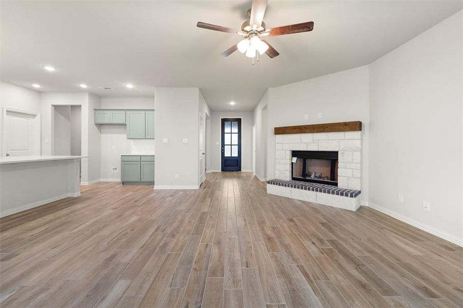 Unfurnished living room with light wood-style flooring, recessed lighting, ceiling fan, and a stone fireplace Unfurnished living room with light wood-style flooring, recessed lighting, ceiling fan, and a stone fireplace