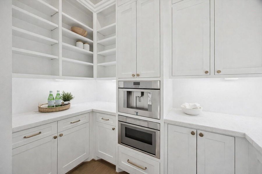 Light filled butler’s pantry featuring custom shaker cabinetry, quartz countertops, and integrated built in coffee system for seamless entertaining. Open shelving, under cabinet lighting, and brushed brass hardware add refined detail while offering generous storage and prep space just off the main kitchen. *Virtually Staged*
