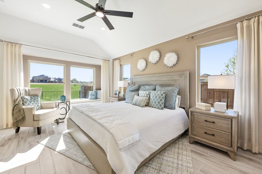 Master bedroom with vaulted ceiling, ceiling fan, king bed, and large windows with backyard views