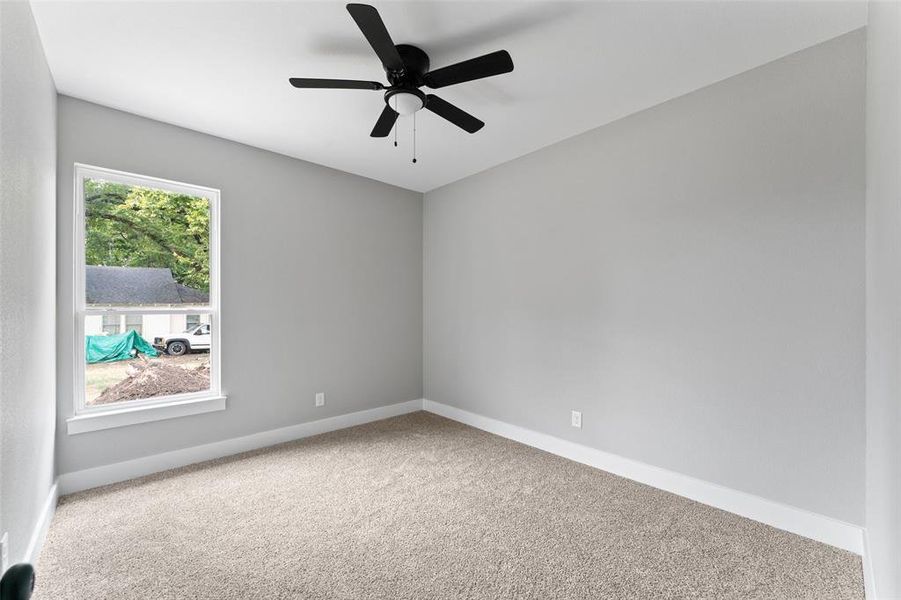 Carpeted spare room with baseboards and ceiling fan