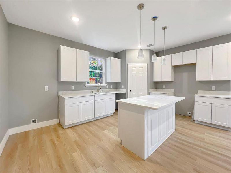 Kitchen with a center island, sink, white cabinets, and light hardwood / wood-style floors