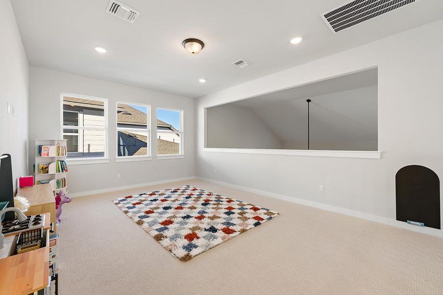 A spacious upper-level loft features wall-to-wall carpeting and large windows overlooking the neighborhood.