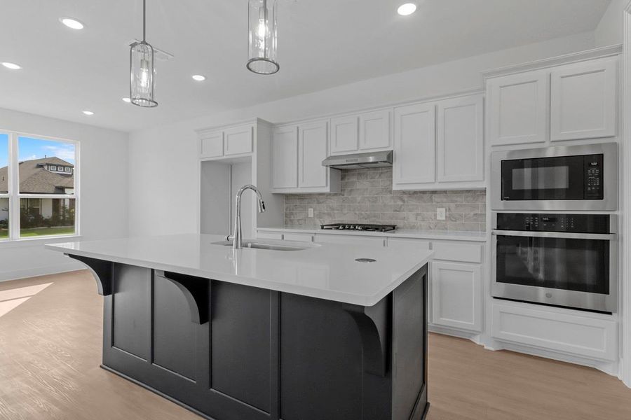 The kitchen features a large island surrounded by white cabinetry and bright windows, creating a perfect space for the family to gather and connect.