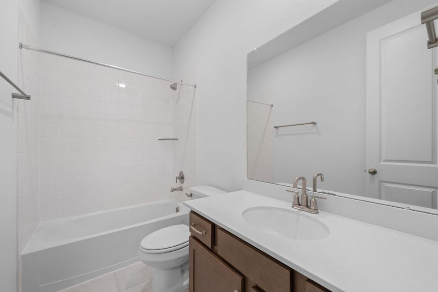 The secondary bath features tile flooring, white cabinetry and light countertops and a shower/tub combo. Perfect for accommodating any visiting family and friends.