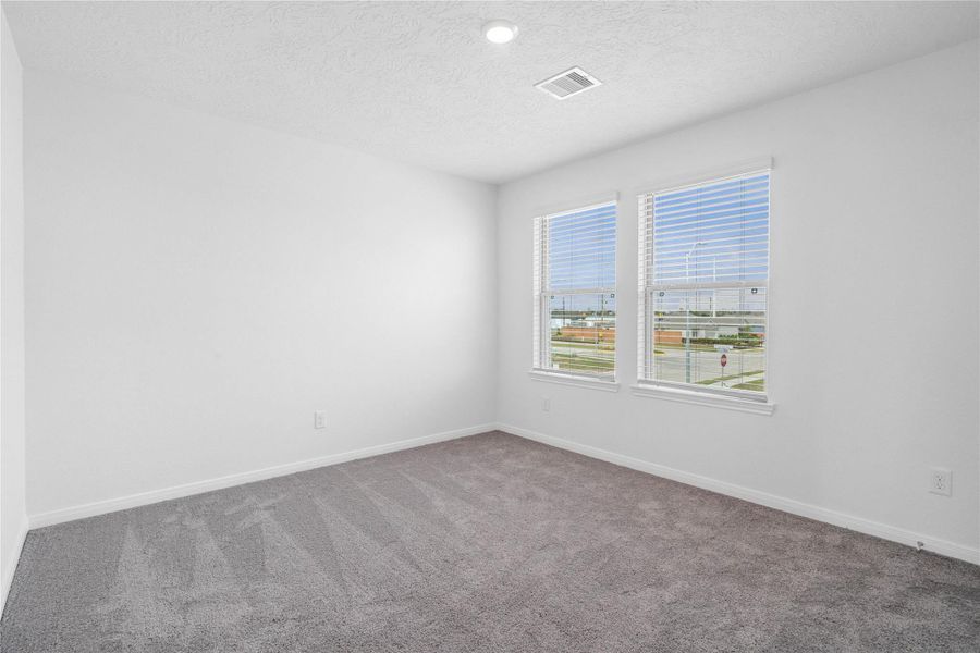 Well appointed secondary bedroom that features plush carpeting, neutral paint tones, recessed lighting, large windows with blinds, and a generously sized closet.