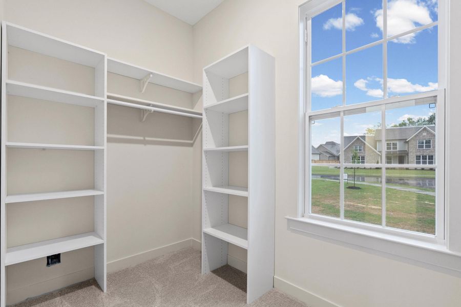 Walk-in closet featuring built-in shelving, hanging rods, and neutral carpet flooring Walk-in closet featuring built-in shelving, hanging rods, and neutral carpet flooring