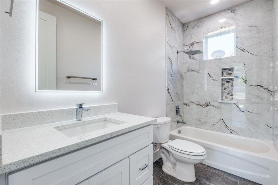 Full bathroom featuring tiled shower / bath, vanity, and toilet