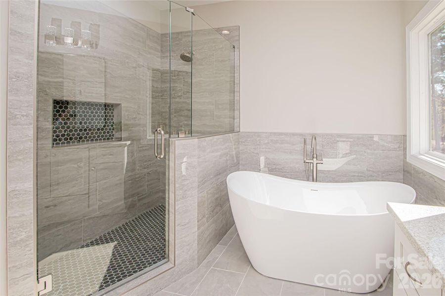Beautifully tiled large shower with brushed nickel fixtures and seamless glass door adds a touch of luxury to the bathroom.