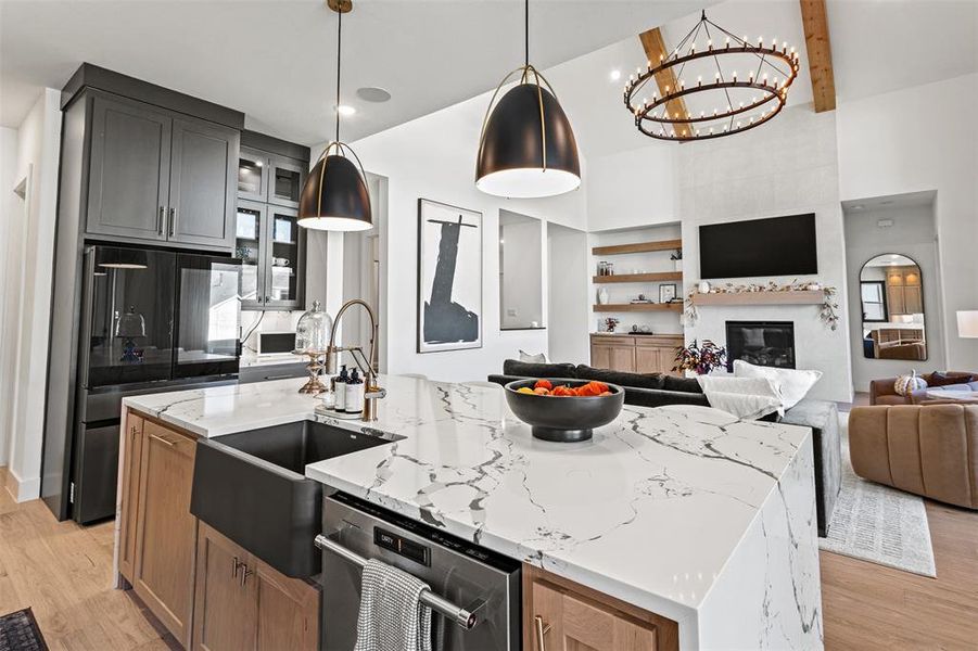 Kitchen featuring light wood finished floors, light stone counters, an island with sink, beam ceiling, and a high ceiling Kitchen featuring light wood finished floors, light stone counters, an island with sink, beam ceiling, and a high ceiling