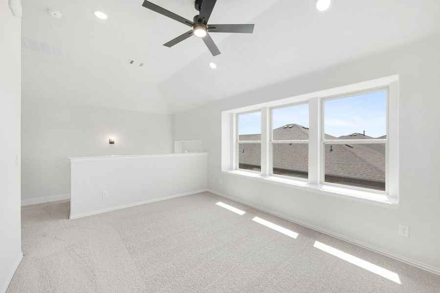 Empty bedroom with vaulted ceiling, ceiling fan, carpet flooring, and large triple windows Empty bedroom with vaulted ceiling, ceiling fan, carpet flooring, and large triple windows