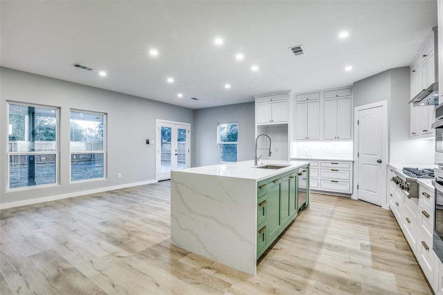 Kitchen with stainless steel gas stovetop, green cabinets, a healthy amount of sunlight, and sink