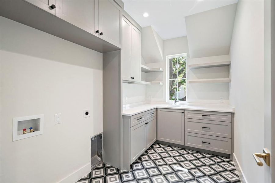 Laundry room featuring cabinets, washer hookup, dark tile patterned flooring, electric dryer hookup, and sink