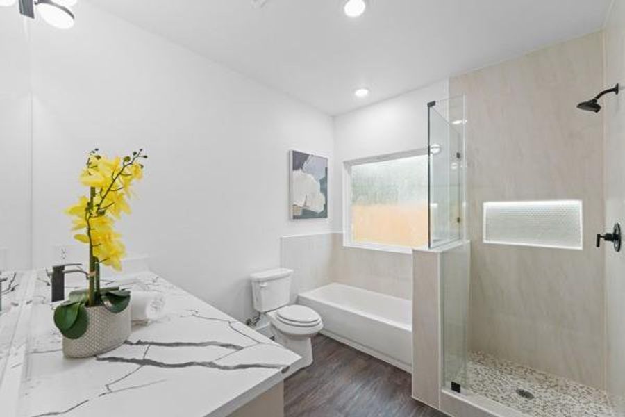 Contemporary bathroom featuring a double vanity with stone countertops, a deep soaking tub, and a separate glass-enclosed shower with a built-in niche Contemporary bathroom featuring a double vanity with stone countertops, a deep soaking tub, and a separate glass-enclosed shower with a built-in niche