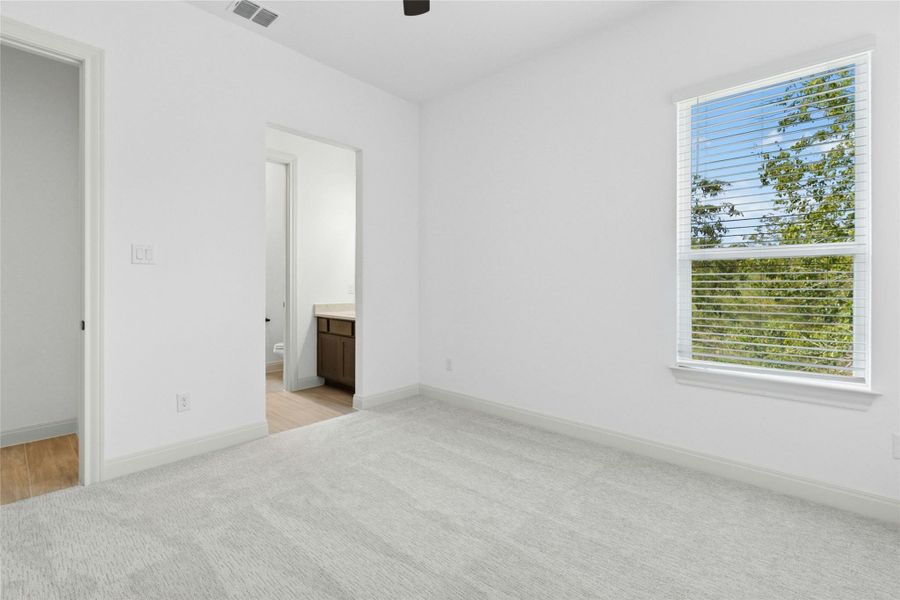 Unfurnished bedroom featuring connected bathroom, light carpet, and ceiling fan Unfurnished bedroom featuring connected bathroom, light carpet, and ceiling fan