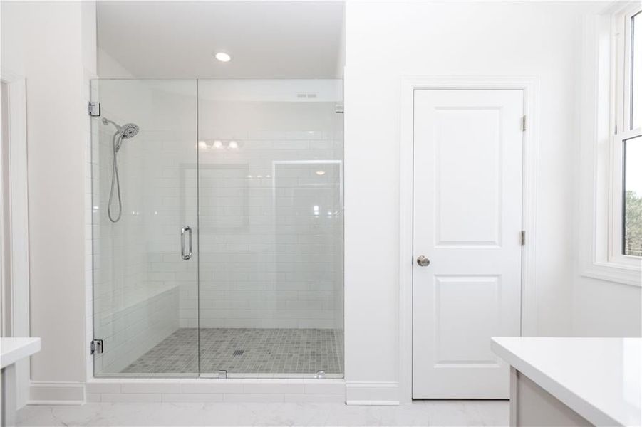 Frameless shower door with tile and bench. Truly lovely layout for a primary bathroom - Pictures represent a previously built home, not the actual home.