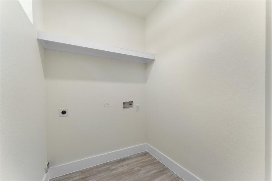 Laundry area with hookup for an electric dryer, light wood finished floors, and gas dryer hookup
