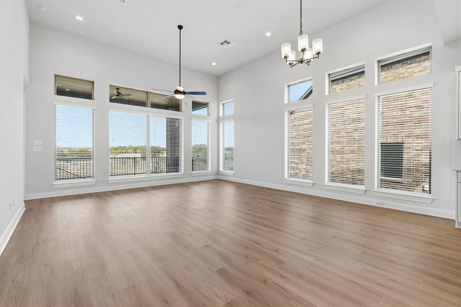 Unfurnished dining area featuring a high ceiling, hanging lights, plenty of natural light, and light wood-type flooring