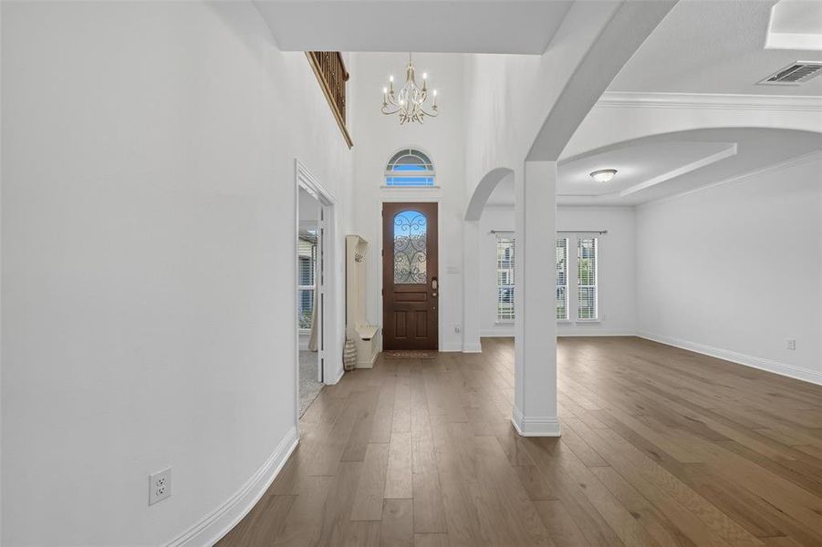Foyer featuring wood finished floors, arched walkways, a chandelier, and a towering ceiling Foyer featuring wood finished floors, arched walkways, a chandelier, and a towering ceiling